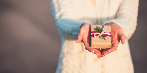 Fototapeta premium Banner of a special little christmas present in woman's hands. A girl is holding a small xmas hand made gift.