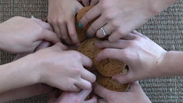 Plate full of oatmeal cookies being snatched up by four hungry children girls.  Close up, top view, macro
