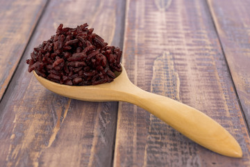 Wooden spoon with brown rice ready to eat. Deep Purple rice, Homnil rice.