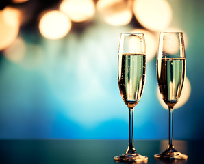 two champagne glasses against holiday lights and fireworks - new year celebration