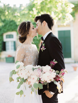 Groom and bride kissing with bunch