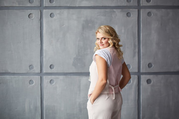 Fototapeta premium Young blonde in light clothes, jacket, trousers and white shoes with a heel in the studio