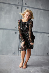 Fototapeta premium Blonde girl in dark light dress barefoot in studio