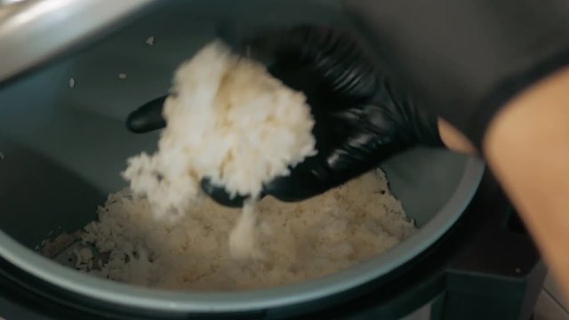 Close-up of professional chef's hands in black gloves making sushi and rolls in a restaurant kitchen. Japanese traditional food. Preparation process. step by step