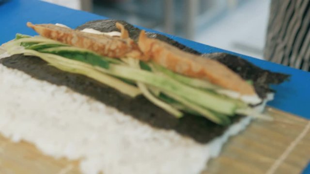 Close-up of professional chef's hands in black gloves making sushi and rolls in a restaurant kitchen. Japanese traditional food. Preparation process. step by step