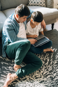 Father and son using laptop at home