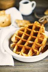 sweet waffle with condensed milk in a plate on a wooden board