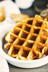 sweet waffle with condensed milk in a plate on a wooden board