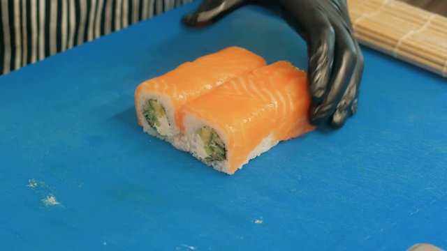 Close-up of professional chef's hands in black gloves making sushi and rolls in a restaurant kitchen. Japanese traditional food. Preparation process. step by step