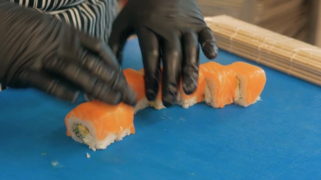 Close-up of professional chef's hands in black gloves making sushi and rolls in a restaurant kitchen. Japanese traditional food. Preparation process. step by step