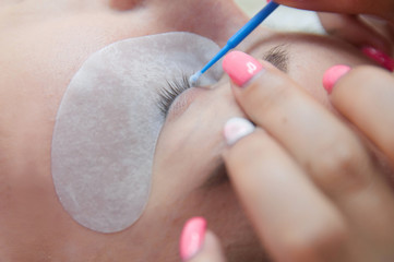 Eyelash extension procedure. Young beautiful woman eye with long false eyelashes. Close up macro shot of fashion eyes in beauty salon.