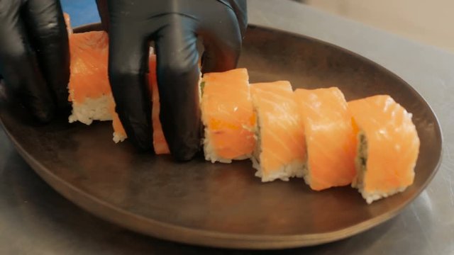 Close-up of professional chef's hands in black gloves making sushi and rolls in a restaurant kitchen. Japanese traditional food. Preparation process. step by step