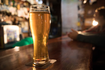 Guy friends drinking beer on the background. Full pint of beer in focus