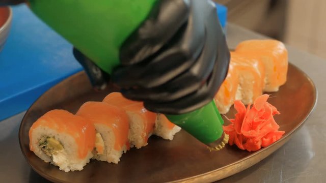 Close-up of professional chef's hands in black gloves making sushi and rolls in a restaurant kitchen. Japanese traditional food. Preparation process. step by step