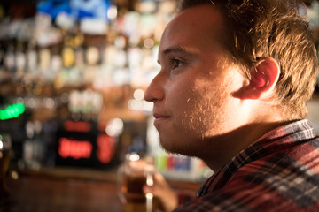 Thoughtful young man drinking beer at the bar counter