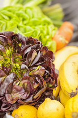 Various vegetables and fruits (tomatoes, salads, onions, cucumbers, lemons) on a kitchen table