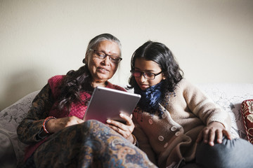 A young girl and a woman looking at a tablet together.