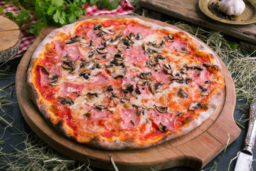 Pizza with ham and mushrooms on wooden background