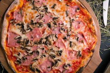 Pizza with ham and mushrooms on wooden background