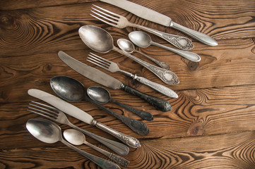 Beautiful vintage cutlery. Silver knives, forks, and spoons on the natural brown wooden background.