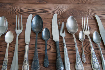 Beautiful vintage cutlery. Silver knives, forks, and spoons on the natural brown wooden background.