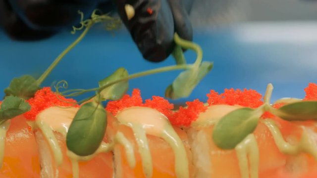 Close-up of professional chef's hands in black gloves making sushi and rolls in a restaurant kitchen. Japanese traditional food. Preparation process. step by step