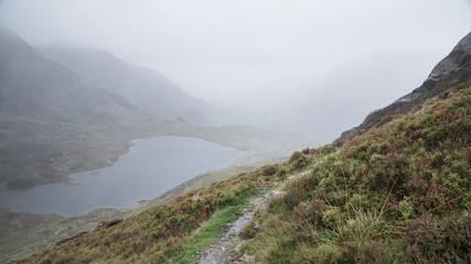 Fototapeta na wymiar Landscape image of Llyn Idwal in Glyders mountain range in Snowdonia during heavy rainfall in Autumn