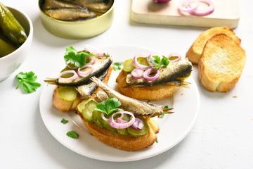 Sandwiches with sprats, marinated cucumber and onion