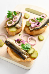 Sandwiches with sprats, marinated cucumber and onion