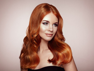 Redhead Girl with Long Healthy and Shiny Curly Hair. Care and Beauty. Beautiful Model Woman with Wavy Hairstyle. Make-Up and Black Dress