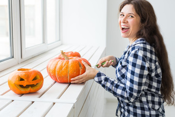 Holidays, halloween, decoration and people concept - close up of woman with pumpkins preparing to...