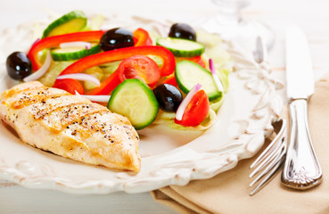 Grilled chicken breast with red pepper, cherry tomatoes, lettuce, black olives, cucumber and fresh rosemary. Home made food. Concept for a tasty and healthy meal. 