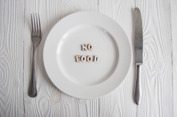 Words on white empty plate from wooden letters: Diet, anorexia and hunger concept. 