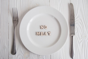 Word Meat on white empty plate from wooden letters: Diet, anorexia, hunger and vedetarian concept. 