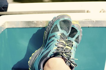 Relaxing with feet up on a boat, male in training shoes, filter applied 