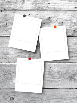 Three blank square instant photo frames on white wooden background