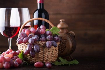 Ripe grapes in wicker basket on wooden background.