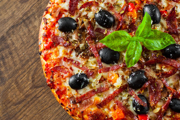 Pizza with Mozzarella cheese, salami, pepper, ham, pepperoni, olives, Spices and Fresh Basil. Italian pizza on wooden background