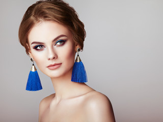 Beautiful Woman with Large Earrings Tassels jewelry Blue color. Perfect Makeup and Elegant Hairstyle. Blue Make-up Arrows