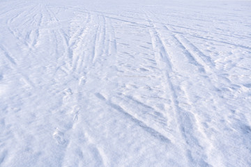 Fototapeta na wymiar Traces of sledge runners and ski on white freshly fallen snow.