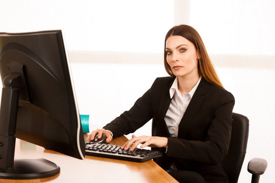 Attractive young business woman works at her desk in the office