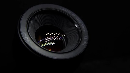 Close Up of DSLR Camera Lens Canon 50mm f1.8 in the Dark. Moving Light Reflections in Objective Glasses.