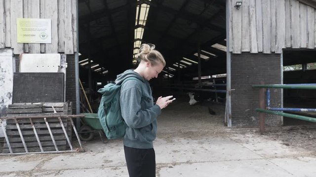 Young Woman Looking at Her Phone on an Organic Dairy Farm