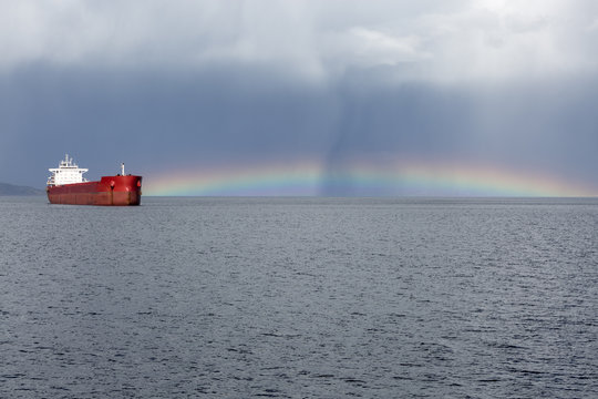 Anchored ship at bay with a rainbow