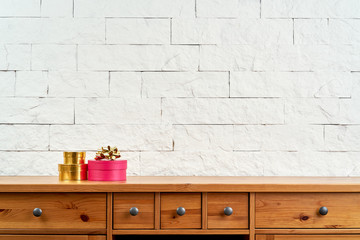 Christmas decoration with a gift on an old shelf on the background of a white brick wall