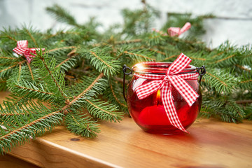 Christmas decoration with twigs of spruce and a red lantern on an old shelf on the background of a white brick wall