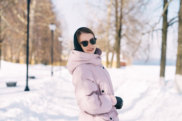Young stylish woman walking at the park on a sunny winter day. Winter Weekend Recreation.