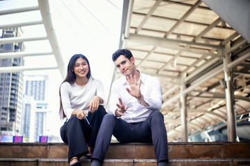 Fototapeta premium Two young couple sitting on staircase and discussing at outdoor, urban lifestyle.