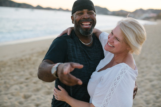 Fun Middle Aged Couple Enjoying Quality Time On The Beach At Sun