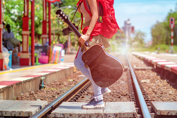woman traveler holding guitar walking across railway station from side to another side, traveling woman, backpacker walking, find hurry destination